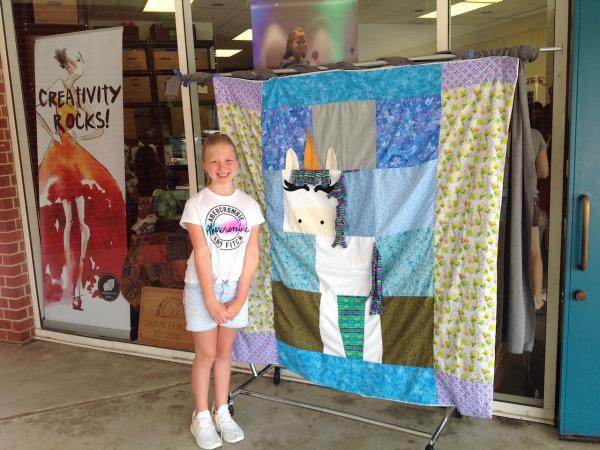 A sewist and her finished unicorn quilt at Creativity Shell